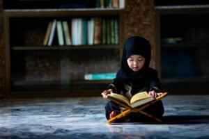 Asian Indonesian Muslim kid is reading the holy Quran.
